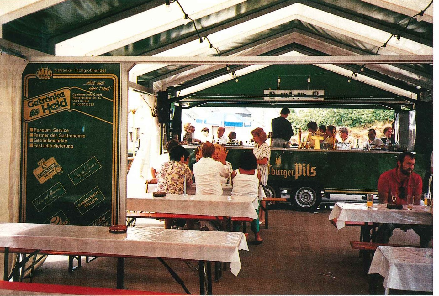 Mobiler Ausschankwagen von Getränke Heid im Festzelt mit Gästen an Biertischgarnituren