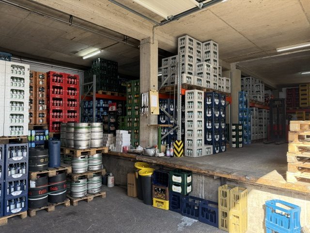Vielfältiges Getränkesortiment: bunte Kästen und Fässer im Lager